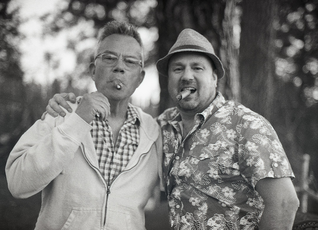 Two friends posing together with cigars