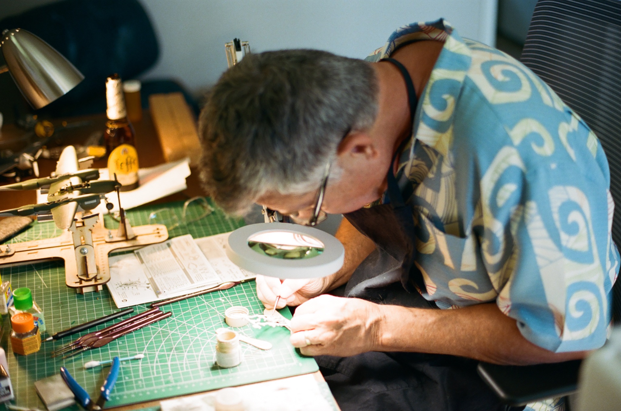 Hank painting a small part beneath a magnifying lamp