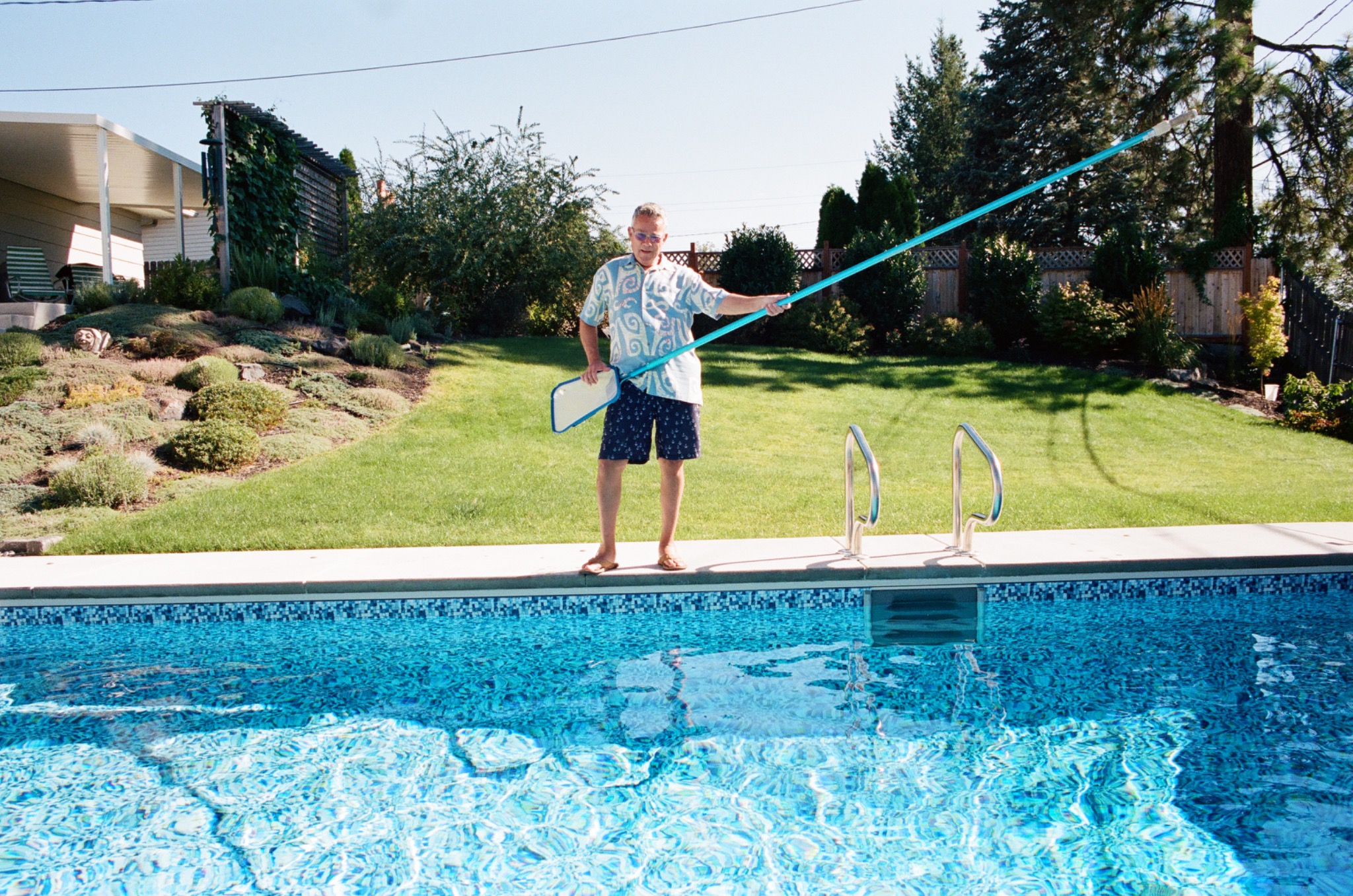 Hank standing by the pool with a long skimmer