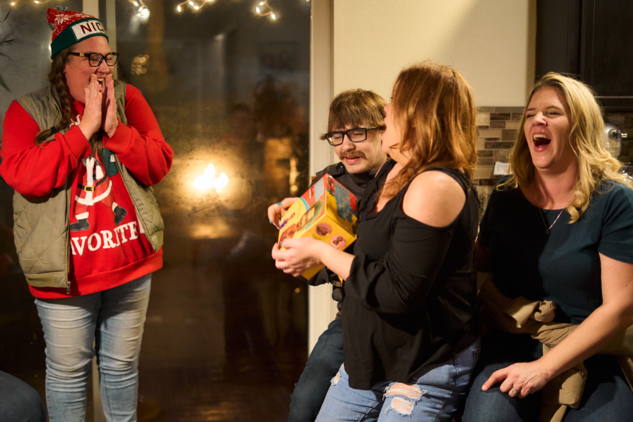 Friends laughing over a newly opened Christmas gift